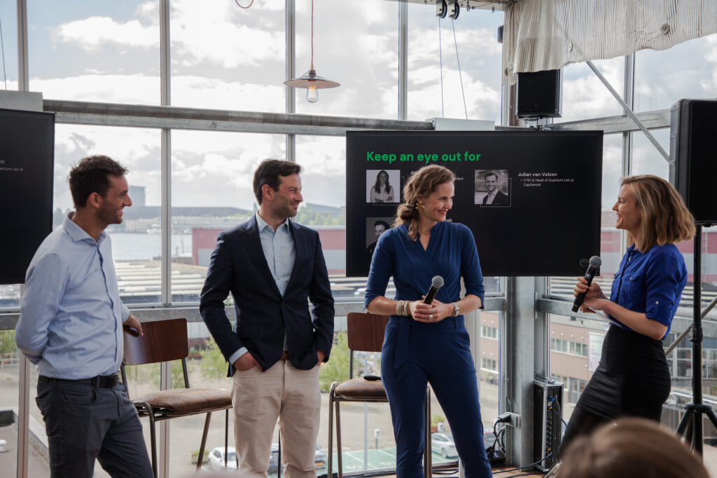Anke Huiskes from NP Hard Ventures, Julian van Velzen from Capgemini, and Jaap van den Broek participate in a panel discussion, moderated by a female host, in a modern conference setting.